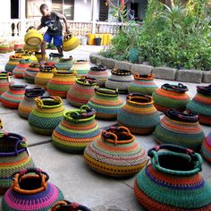 colorful baskets are arranged on the ground in front of a building with a man standing next to them