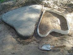 a shovel laying in the sand next to a stone slab with a hole cut into it