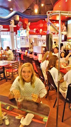 a woman sitting at a table with food in front of her and people behind her