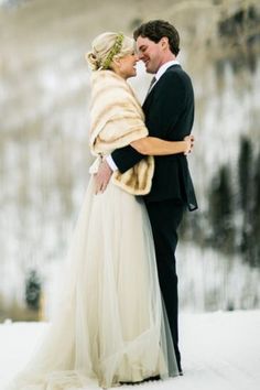 a bride and groom embracing in the snow