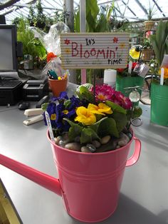 a pink bucket filled with lots of flowers on top of a table next to a sign that says bloomin'time