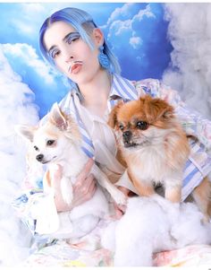 a woman with blue hair holding three small dogs