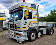 a white and yellow truck parked on top of a brick road