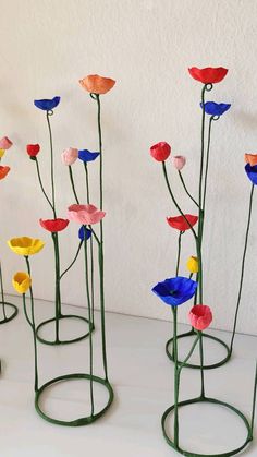 four metal flower sculptures sitting on top of a white table next to eachother