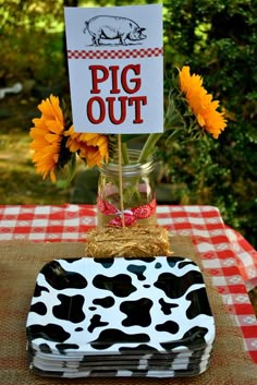 a table topped with a vase filled with sunflowers and a sign that says pig out