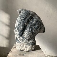 a sculpture is shown on top of a block of concrete and has an image of a man's head in the middle