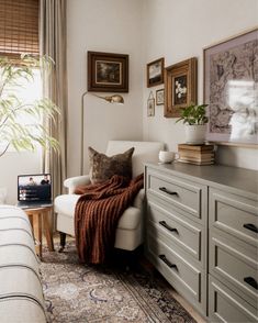 a living room with a couch, dresser and pictures on the wall above it's headboard