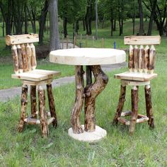 three wooden stools and a table made out of logs in the grass near trees