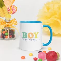 a white coffee mug filled with candy and lollipops next to a yellow flower