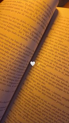 an open book with a white heart on the page and light shining from it's corner