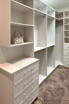 a walk in closet with white shelving and drawers