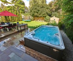 a hot tub sitting on top of a wooden deck next to a lush green field