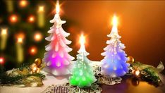 three lit candles sitting on top of a doily next to a small christmas tree