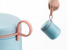 a person is holding a cup and pulling it out of a blue container with pink handles