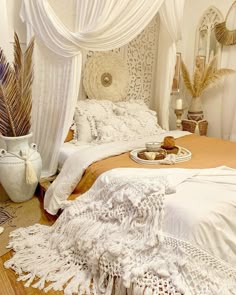 a bed with white sheets and pillows on top of it next to two vases