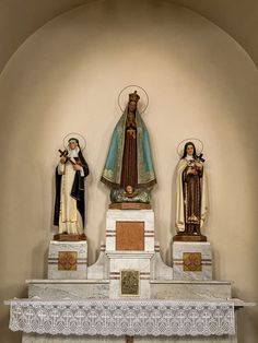 three statues of the virgin mary and jesus on top of a mantle in a church