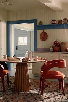 two chairs and a table in a room with blue trim on the walls, one chair has an orange upholstered seat