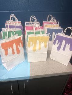 five bags with paint on them sitting on a counter top in front of a blue wall