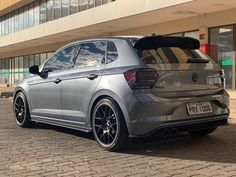 the rear end of a silver volkswagen car parked in front of a building