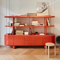 an orange shelf with books and magazines on it