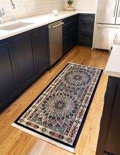 a large rug in the middle of a kitchen with dark cabinets and white counter tops