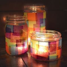 three jars are sitting on a table with some lights in the jar and one is empty