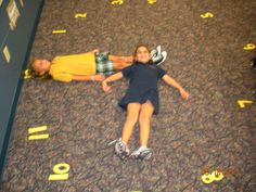 two children are laying on the floor in an area that has yellow markers all over it