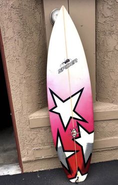 a surfboard is propped up against the wall in front of a door with graffiti on it