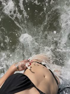 a woman laying on top of a surfboard in the ocean next to a wave