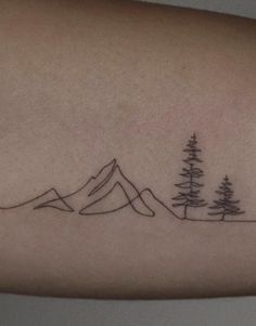 a tattoo with trees and mountains on the arm