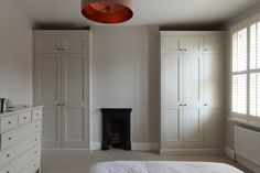 an empty bedroom with white furniture and large closets on either side of the bed