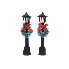 two christmas wreaths on top of black posts with red bows and lights attached to them