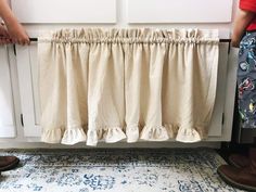 two people standing next to each other in front of a radiator with curtains