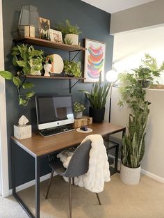 a desk with a laptop computer on top of it next to a potted plant