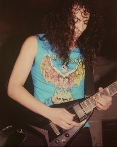 a man with long hair playing an electric guitar