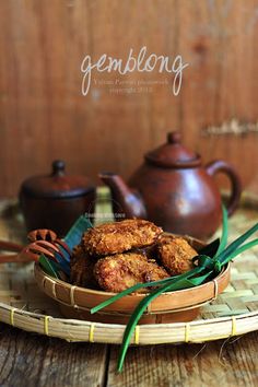 some food is sitting in a bowl on a bamboo tray next to teapots