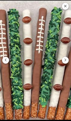 four football themed dessert sticks are arranged in the shape of grass and footballs on them