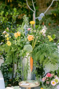 a vase filled with flowers sitting on top of a wooden table next to other plants