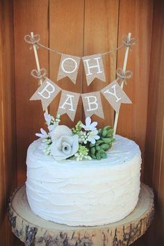 a white cake sitting on top of a wooden table next to a sign that says oh baby