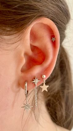 a close up of a person's ear with stars and chains on the side