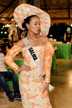 a woman in an orange and white dress is standing with her hands on her hips