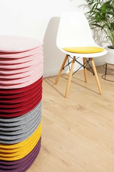 a stack of multicolored plates sitting on top of a wooden floor next to a white chair