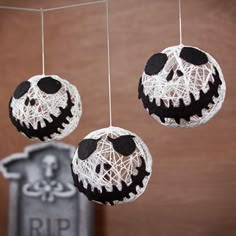 three halloween decorations hanging from strings on a wooden wall with the caption saying,