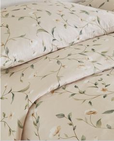 the comforter is made up with white flowers and green leaves on beige fabric,