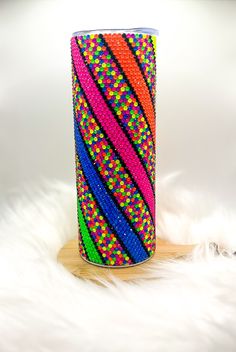 a colorful vase sitting on top of a white fur covered floor next to a wooden stand