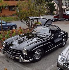 an old black mercedes sports car parked in a parking lot next to other classic cars