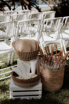 an outdoor ceremony with white chairs and wicker baskets filled with napkins on top of each other