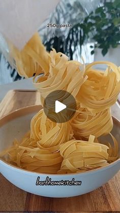 pasta being cooked in a white bowl on top of a wooden table with the video title below it