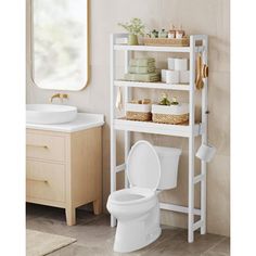 a white toilet sitting next to a sink in a bathroom under a mirror and shelf