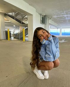 a woman kneeling down in an empty parking garage